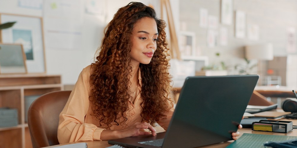 A woman running a small business looks at her laptop while enjoying the benefits of QuickBooks cloud hosting from Rightworks.