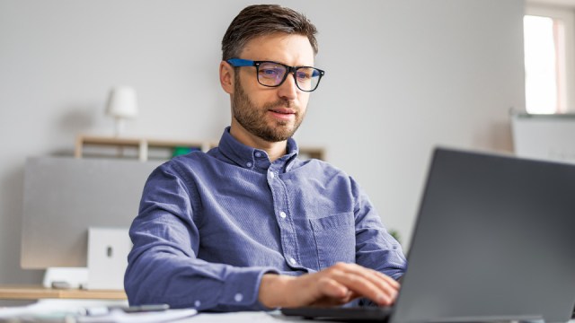 A man looks at his laptop, reviewing the benefits of QuickBooks Desktop Enterprise.