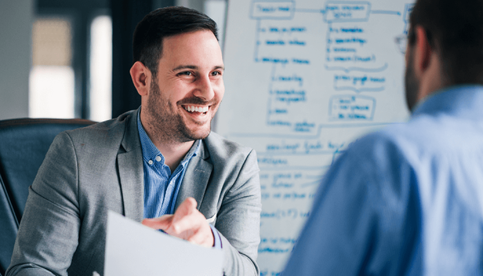 Two men talking at a job interview with one holding a resume.