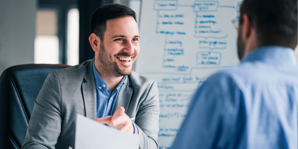 Two men talking at a job interview with one holding a resume.