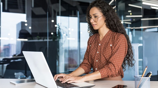 Female CPA typing on a laptop with glass background