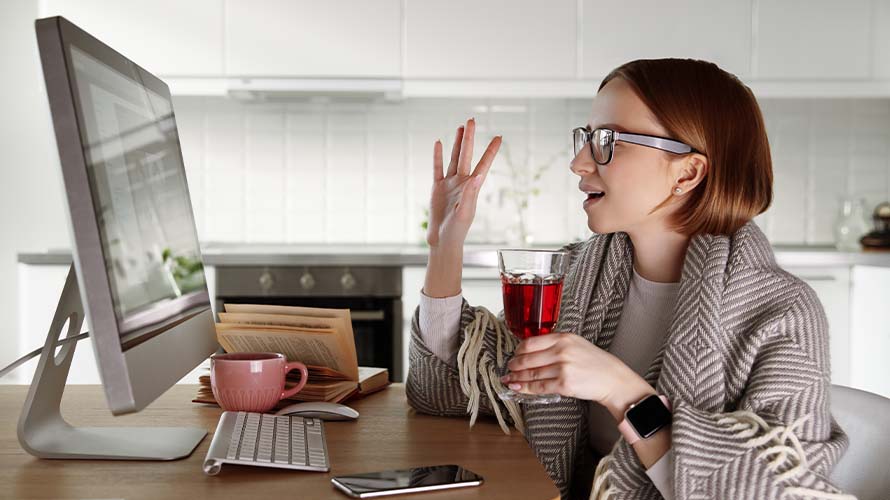 A remote worker sits at her desk on a video meeting to go over securing her workstation.