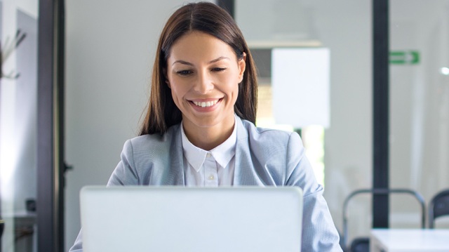 Female business worker smiling and confident working on her laptop thanks to her cloud security solution.