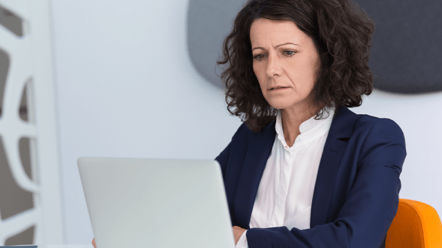 A woman sits in front of a laptop, looking concerned about how AI could affect her accounting job.