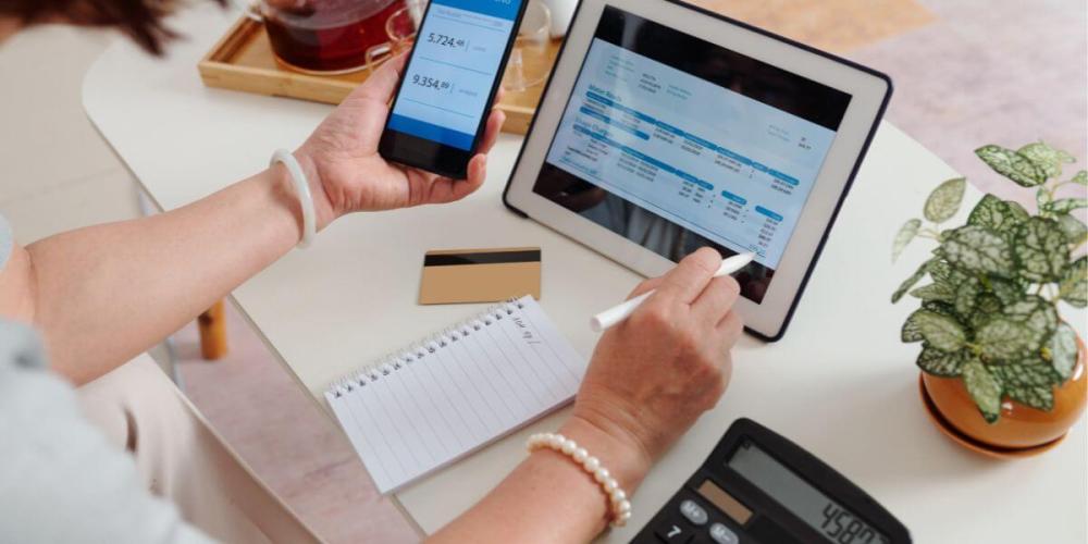 Hands touching a phone and tablet, showing bookkeeping applications