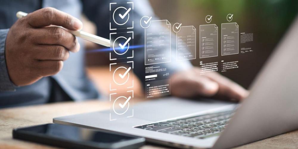 Guy hands in front of a computer screen with checkmarked documents floating in the air