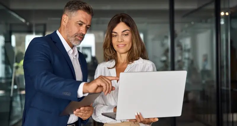 Two people reviewing information on a laptop screen