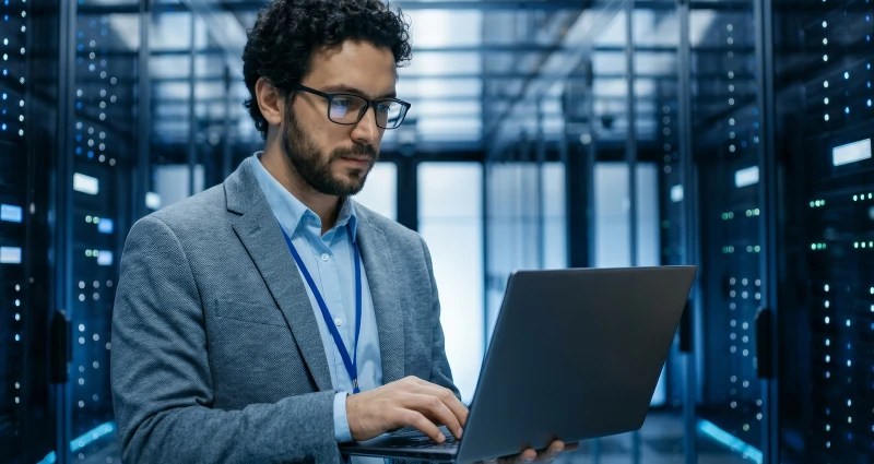 Person on a laptop with server racks behind them